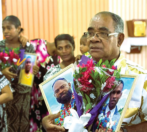 A man carrying flowers and pictures of deceased loved ones.