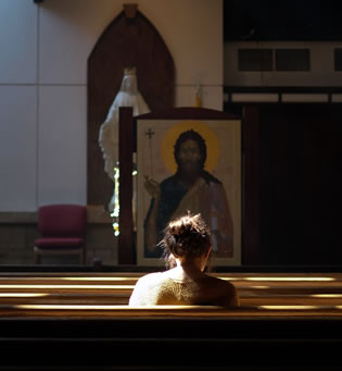 Person sitting in a church pew praying and reflecting.