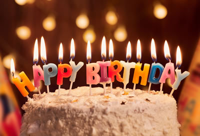 A birthday cake with lit candles that spell Happy Birthday