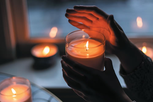 person holding a lit votive candle