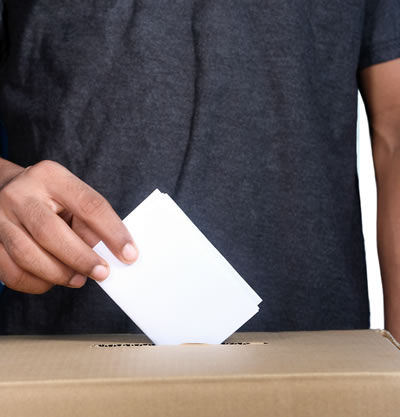 person putting a ballot into the box