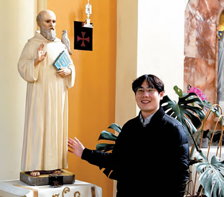 Verano Lee Jeong-Rak standing next to a statue of St. Columban
