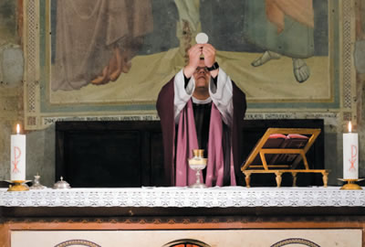 Priest raises the host during Mass