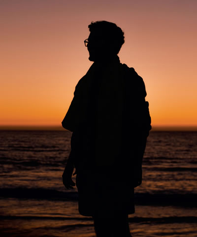 A man looks out over the ocean at twilight