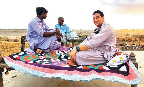 Fr. Pat Visanti (right) sitting on a charpal bed in a Pakistani village