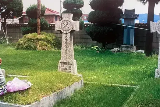 Fr. Ray Collier at his uncle Tony's grave outside Chuncheon Cathedral in Korea during a visit in 2000.