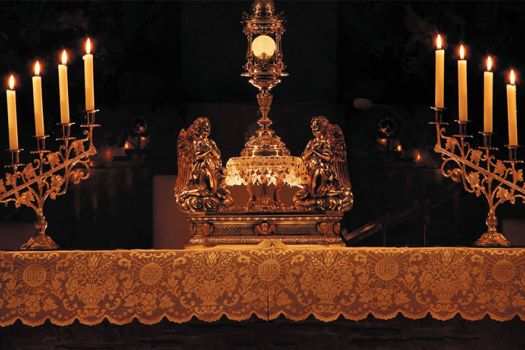 The Exposition of the Blessed Sacrament on the altar with candles lit .