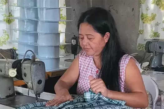 Program worker running fabric through the sewing machine.