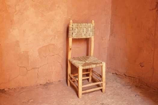 An empty chair sits in a corner surrounded by blank walls