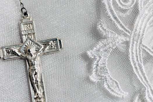 A silver crucifix of a rosary setting on white lace