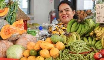 Woman looks smiling from behind her counter at a market in Fiji