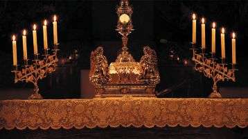The Exposition of the Blessed Sacrament on the altar with candles lit .