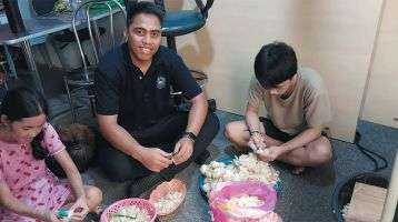 Columban student Matang Moeniba from Kiribati helping a family peel garlic for sale.