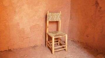 An empty chair sits in a corner surrounded by blank walls