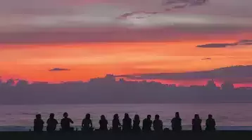 Group of people sitting on a beach at sunset