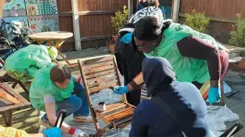 Abi (left, bending) painting garden furniture