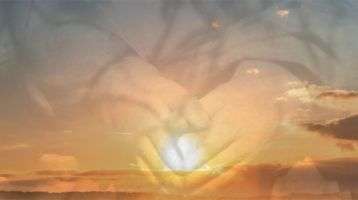 hands superimposed over a sunrise