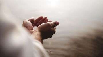 Cupped hands holding the water of baptism