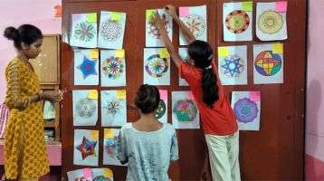 School children hanging their artwork on the wall.