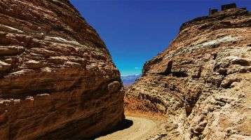 A dirt path between two stoney mountains