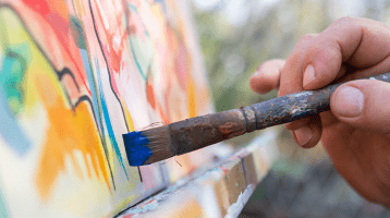 The hand of an artist painting on a canvas.