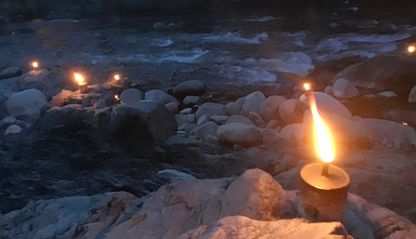 Candles sit on rocks next to a river