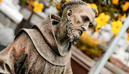 Statue of Saint Francis of Assisi with a serene expression and detailed features, holding a crucifix. São João Batista Cemetery, Rio de Janeiro, Brazil