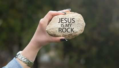 A hand holding a rock with the words Jesus Is My Rock