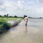 Man walks in floodwater in Tajeli Village