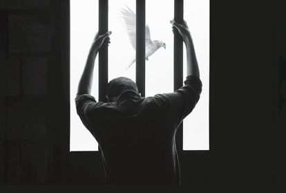A man looking out a barred window