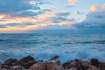 Ocean waves batter a rocky shore at dusk