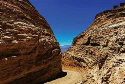 A dirt path between two stoney mountains