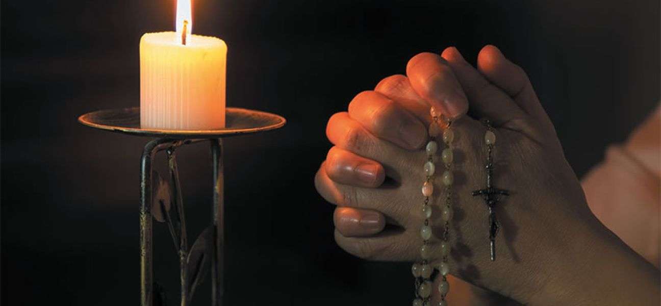 Praying the rosary in front of a lit candle