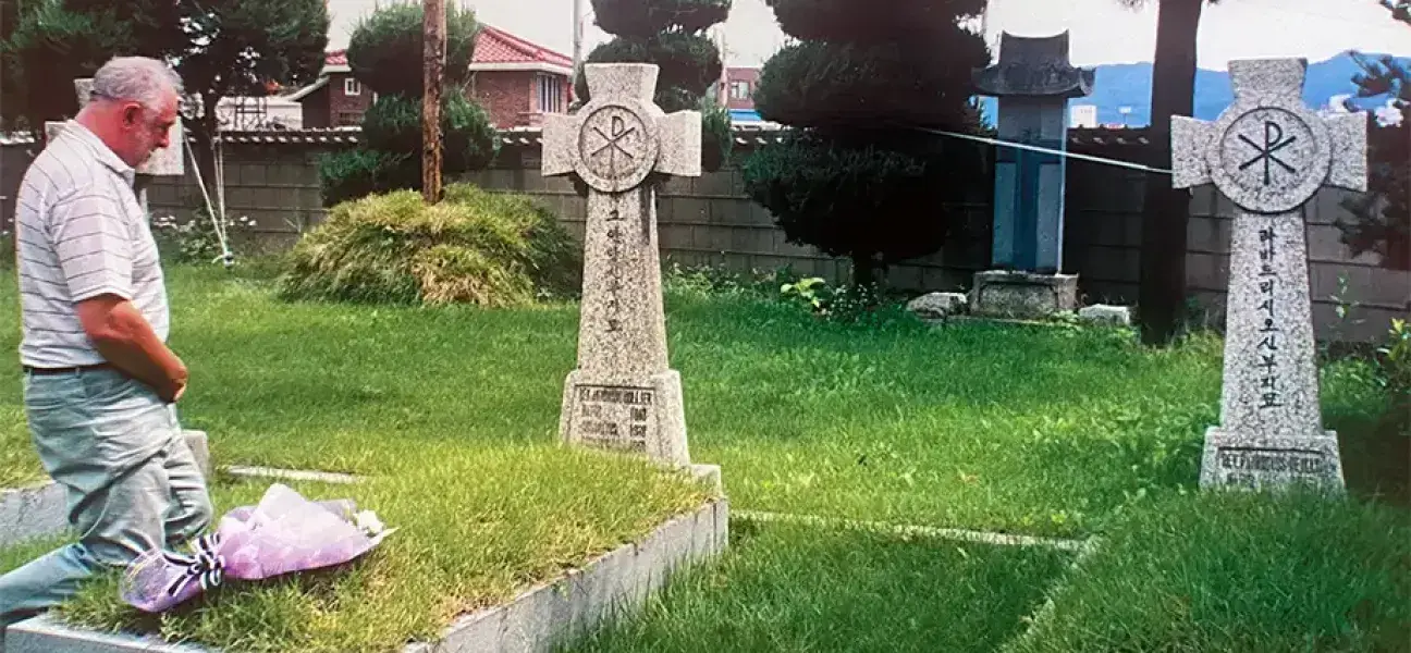 Fr. Ray Collier at his uncle Tony's grave outside Chuncheon Cathedral in Korea during a visit in 2000.