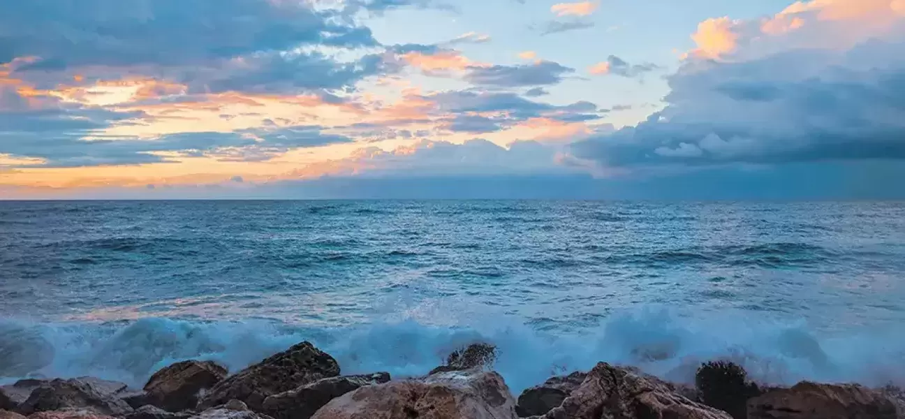 Ocean waves batter a rocky shore at dusk