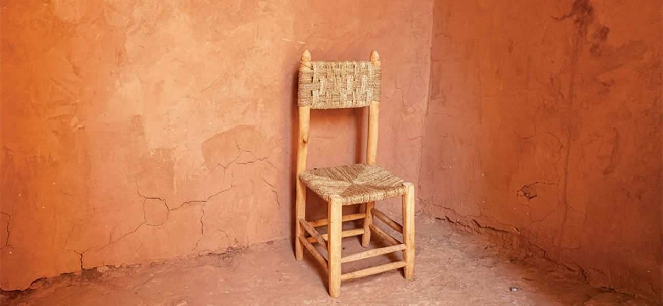 An empty chair sits in a corner surrounded by blank walls