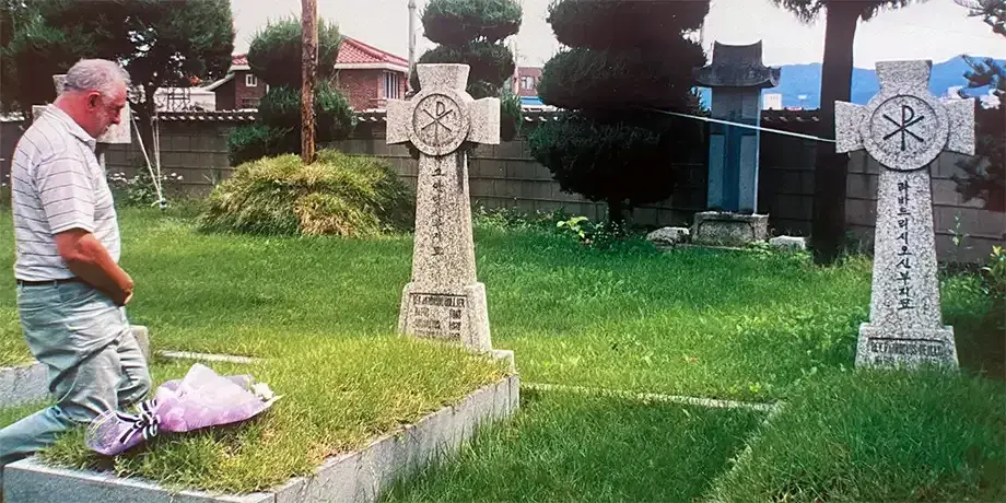 Fr. Ray Collier at his uncle Tony's grave outside Chuncheon Cathedral in Korea during a visit in 2000.