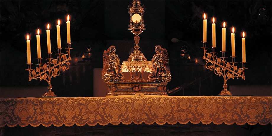 The Exposition of the Blessed Sacrament on the altar with candles lit .