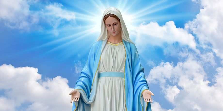 Statue of the Blessed Virgin Mary in front of a blue sky with puffy clouds.