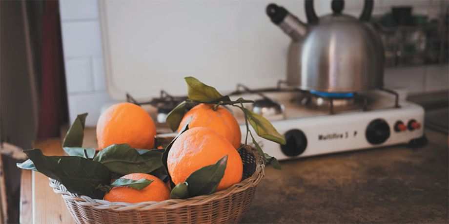 Basket of oranges and a teapot warming on the stove