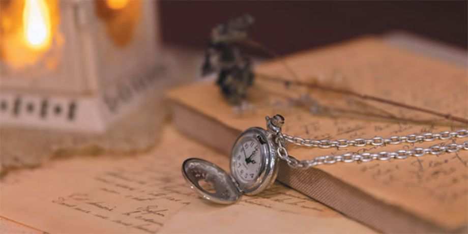 A watch, candle and letters on a desk
