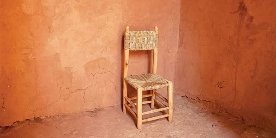 An empty chair sits in a corner surrounded by blank walls
