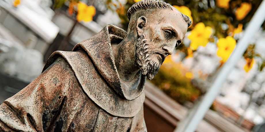 Statue of Saint Francis of Assisi with a serene expression and detailed features, holding a crucifix. São João Batista Cemetery, Rio de Janeiro, Brazil