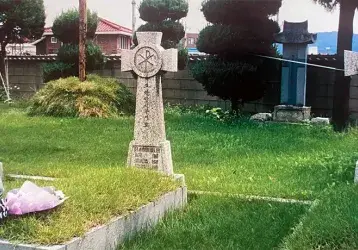Fr. Ray Collier at his uncle Tony's grave outside Chuncheon Cathedral in Korea during a visit in 2000.