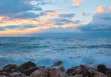 Ocean waves batter a rocky shore at dusk