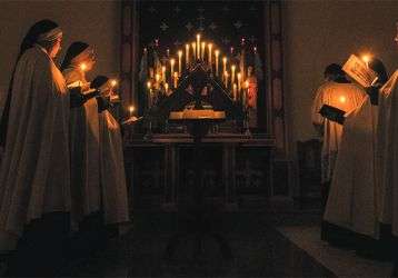 Nuns praying by candlelight in church