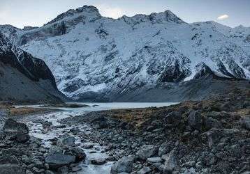 Snow-covered mountains with stream of glacial runoff.