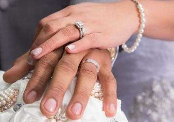 Married couple's hands clasped together showing wedding rings.